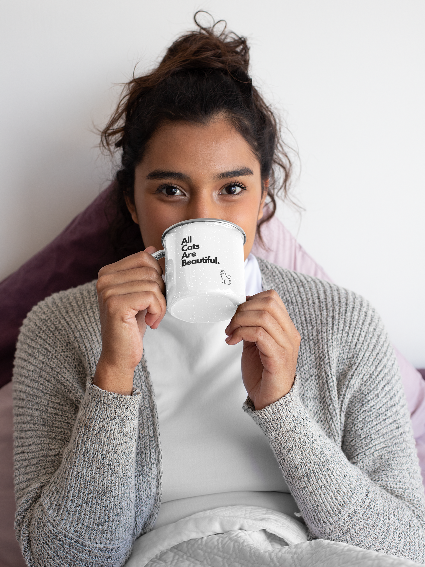 A woman with long brown hair drinking from A white mug featuring the bold statement 'all cats are bastards' in black block letters, complete with an outline of a cat below.